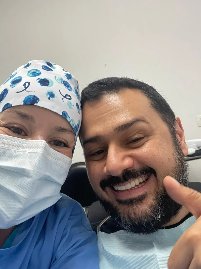 Smiling patient giving a thumbs-up beside a clinician at the clinic.