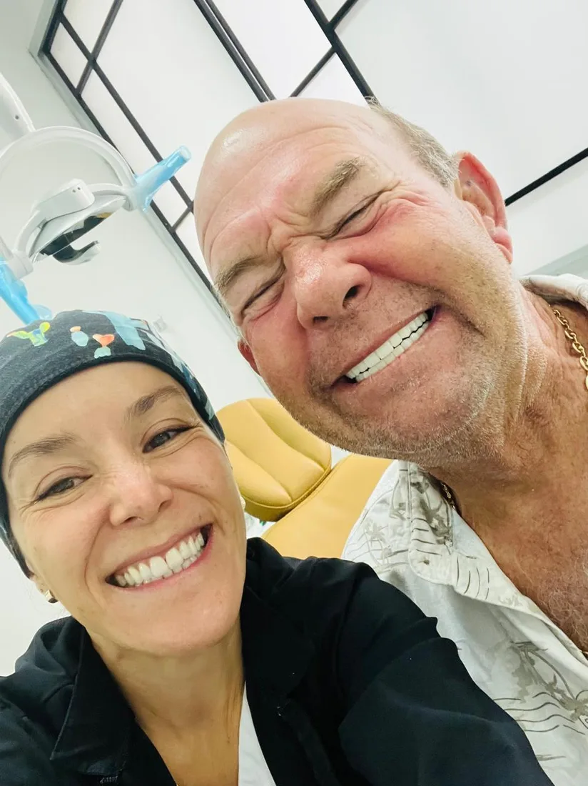 Smiling patient posing with a clinician in a treatment room.
