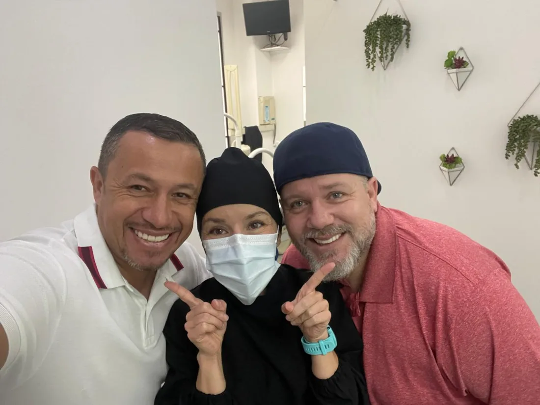 Two smiling patients posing with a clinician at the clinic.